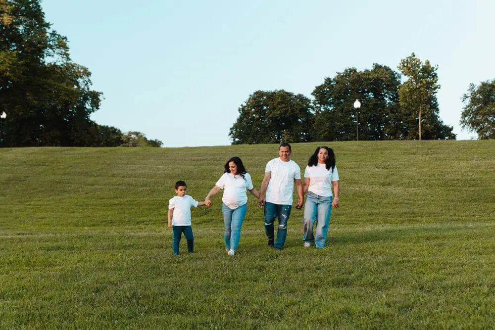 Expecting family walking hand in hand through a park during a maternity photo session by Create With Amy in Maryland
