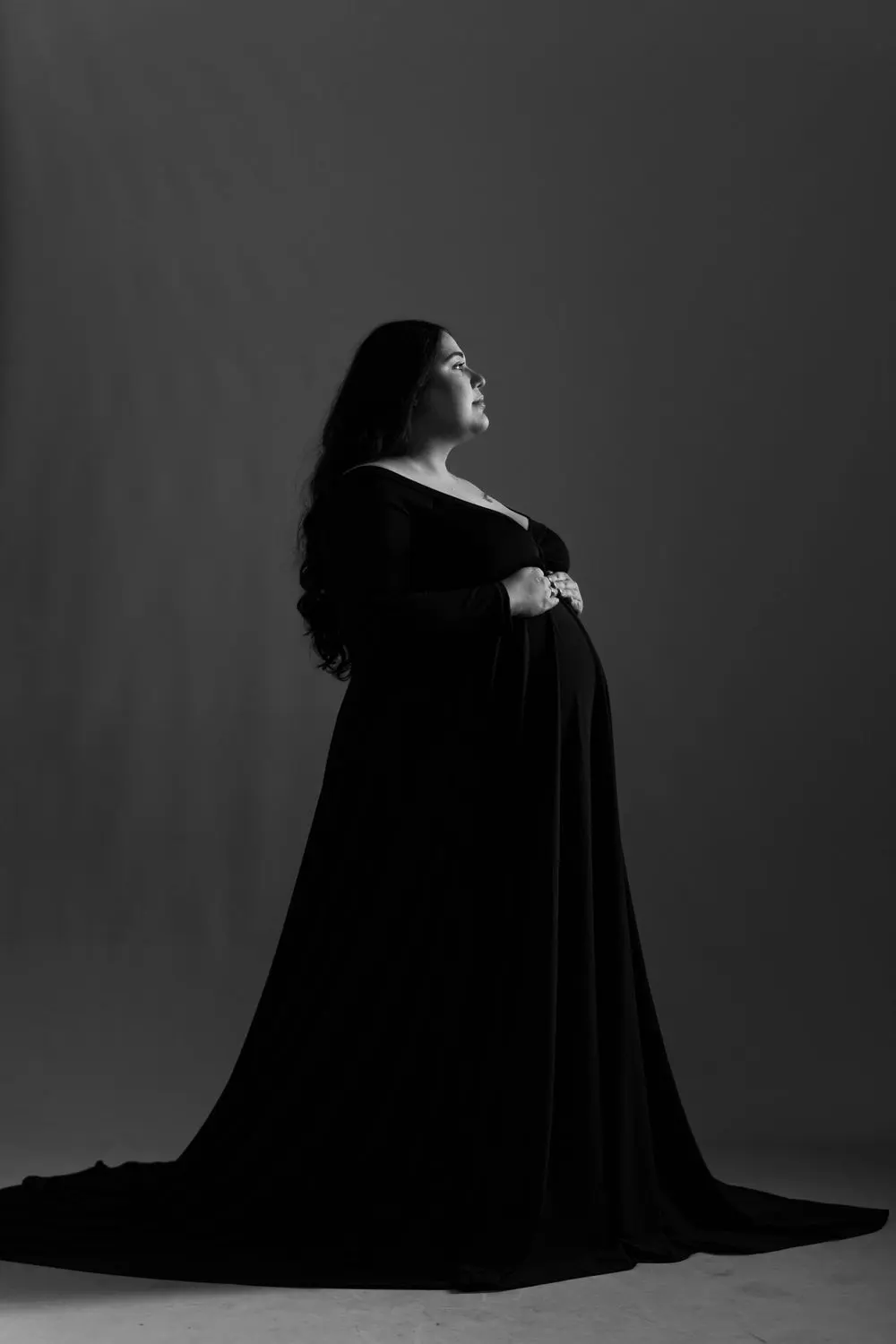 Maternity profile portrait in a black gown against a gray backdrop, photographed by Create With Amy, maternity photographer in Maryland
