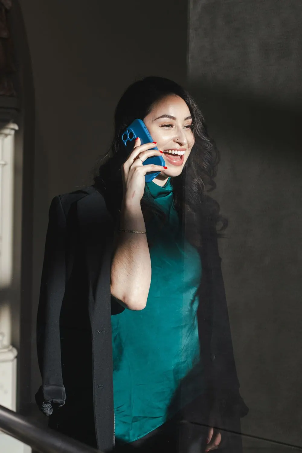 Business owner laughing on a phone call in dramatic window light during a content session by Create With Amy, social media videographer in Baltimore