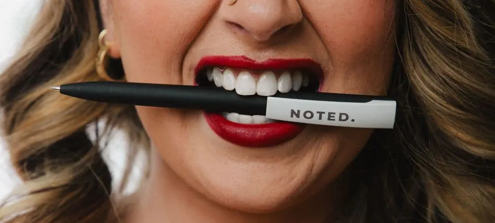 Bold brand content close-up of a business owner biting a branded pen, from a Create With Amy content creation package session